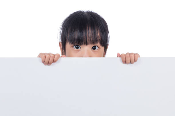 istock Asian Chinese little girl peeping behind white board 831256912