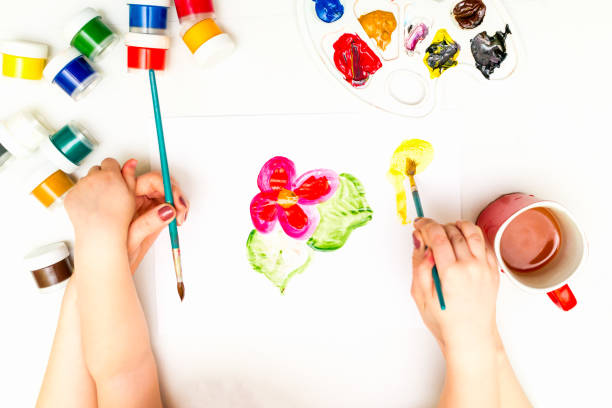 istock Child's hands painting a flower 831271964