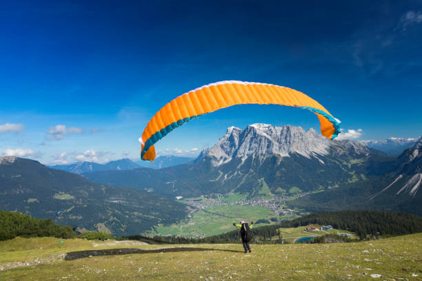 gleitschirmfliegen in den alpen, tandem-gleitschirm starten einen flug, berg zugspitze, alpen - paragliding sport austria parachuting stock-fotos und bilder