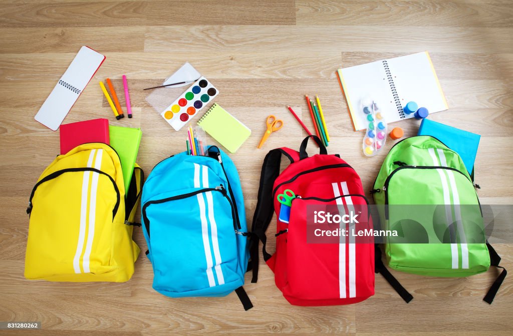 Colourful children schoolbags on wooden floor Colourful children schoolbags on wooden floor. Backpacks with school accessories Backpack Stock Photo