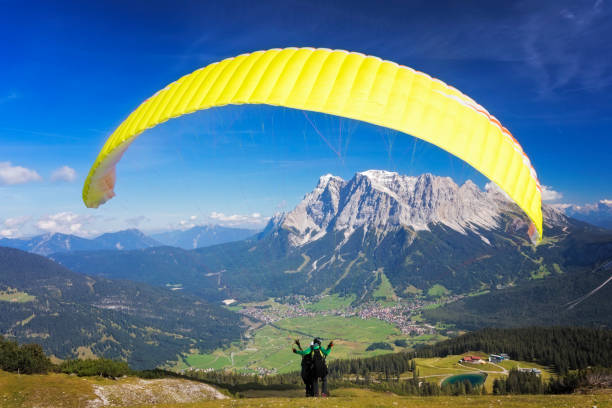 gleitschirmfliegen in den alpen, tandem-gleitschirm starten einen flug, berg zugspitze, alpen - paragliding sport austria parachuting stock-fotos und bilder