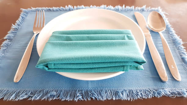 istock Green arpon on white plate with spoon, fork, knife on the blue napery 831284140