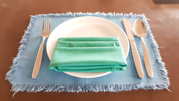 istock Green arpon on white plate with spoon, fork, knife on the blue napery 831284162