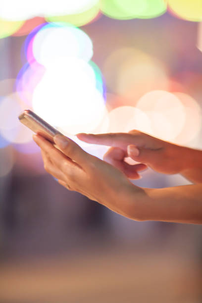 istock Woman using her mobile phone, city skyline night light background 831314246