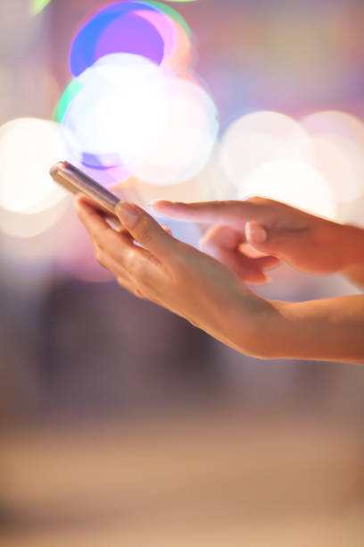 istock Woman using her mobile phone, city skyline night light background 831314292