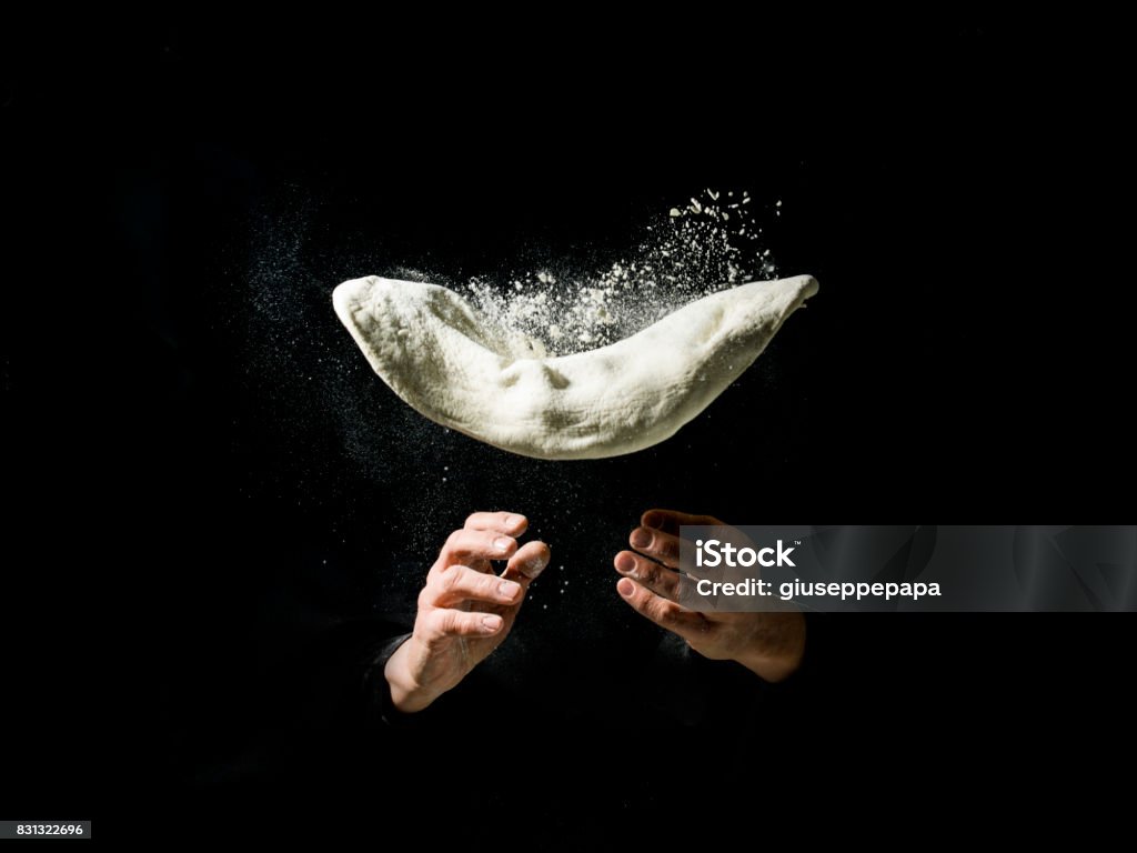 Pizza cook to work with flying pizza dough Fliying pizza dough with flour, on drak background Pizza Stock Photo