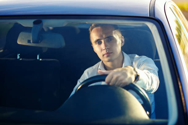 istock Attractive handsome smiling man in white shirt driving an expensive car 831330408