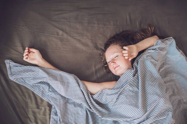 istock Beautiful young woman lying down in bed and sleeping, top view. Do not get enough sleep concept 831333156