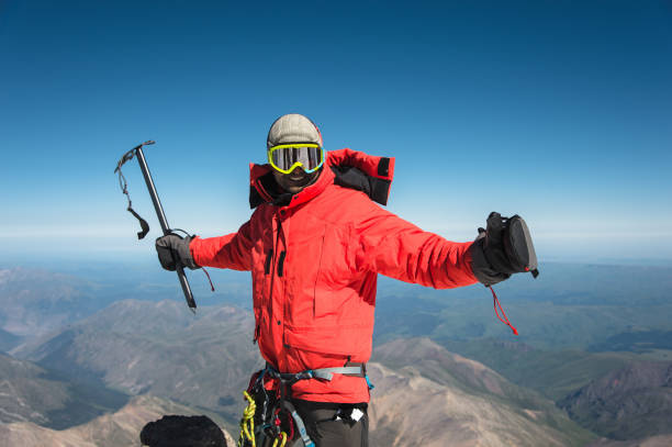 profesjonalny turysta na szczycie skały z rękami do góry jest zadowolony z kolejnego zwycięstwa wznoszenia - on top of mountain peak success cold zdjęcia i obrazy z banku zdjęć