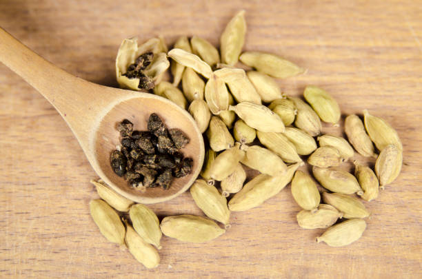 cardamome en coquille et graine dans la cuillère de bois à bord. fermer la vue de dessus d’épices parfum. - cardamome photos et images de collection
