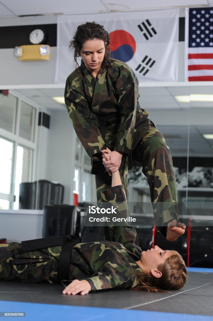 Taken Down and Finish Martial artist finishing her opponent with a stomp. Barefoot Stock Photo