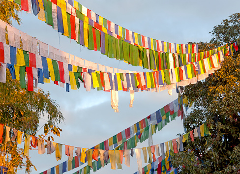 Buddhist Prayer flags, West Bengal, India. Buddhist Prayer flags as criss-crossing streamers, with multi-coloured colourful material of yellow,white and blue wave in the breeze of the Himalayas- a talisman of the buddhist faith or religion that worships the Buddha