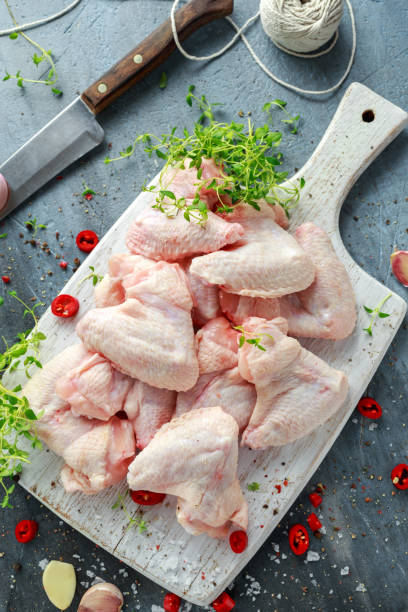 istock Fresh raw chicken wings on a white cutting board with thyme, chilli, salt, pepper, garlic 831348336