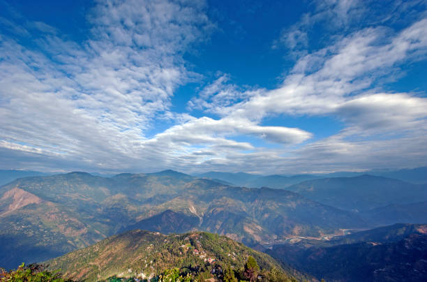Himalayan foothill view, Kalimpong, West Bengal, India. Foothills and sunlit landscape with a whispy cloudscape view from a quiet and tranquil viewpoint in Kalimpong, West Bengal, India