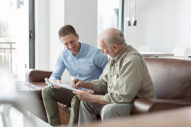Senior man discussing his finances with their advisor Senior man discussing his finances with his advisor in livingroom door to door salesperson photos stock pictures, royalty-free photos & images