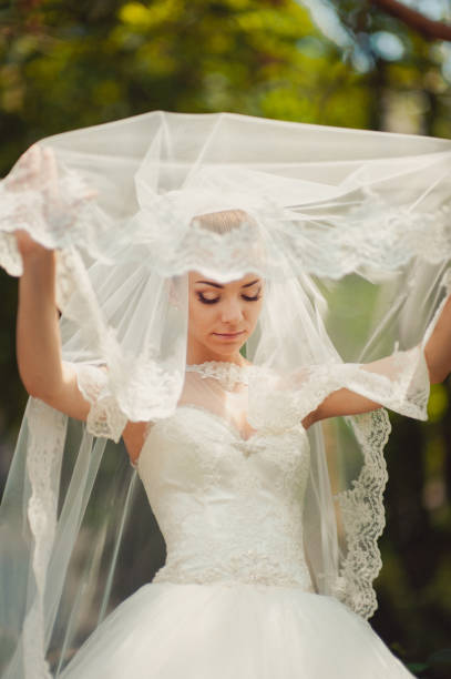 istock Bride hidden by a veil for a walk in the park 831364444