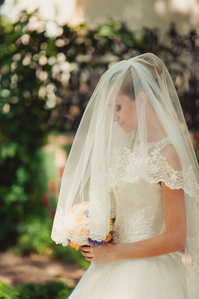 Bride hidden by a veil for a walk in the park