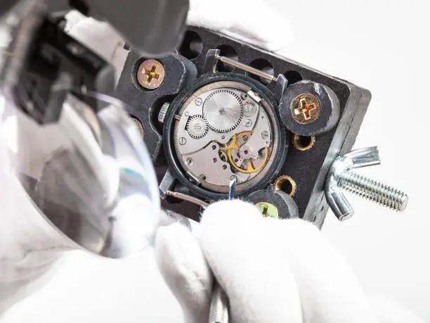 watchmaker workshop - watchmaker in head-mounted magnifier repairs old watch with screwdriver