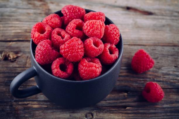 istock Fresh ripe organic raspberry in a mug on a wooden background 831367608
