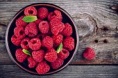 Fresh ripe organic raspberry in a plate on a wooden background