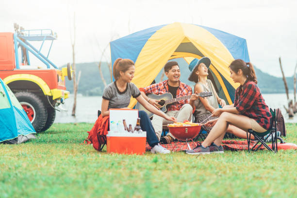 friends having fun eating barbecue outdoor while camping
