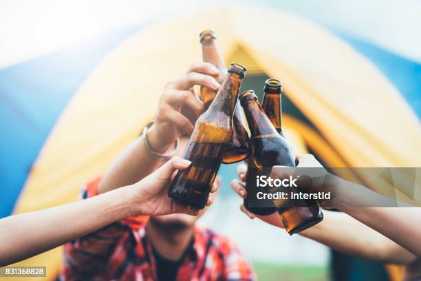 Friends Clinking Bottle Of Beer Stock Photo - Download Image Now - Beer - Alcohol, Celebratory Toast, Barbecue - Meal