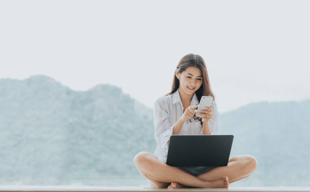 istock Asian woman using smartphone mobile and laptop while sitting 831368852