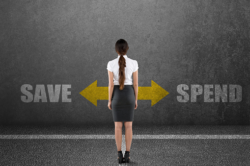 Rear view of businesswoman with spend or save choice on wall