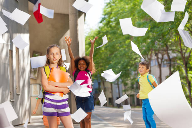istock Kids throw papers in the air with school on back 831382088