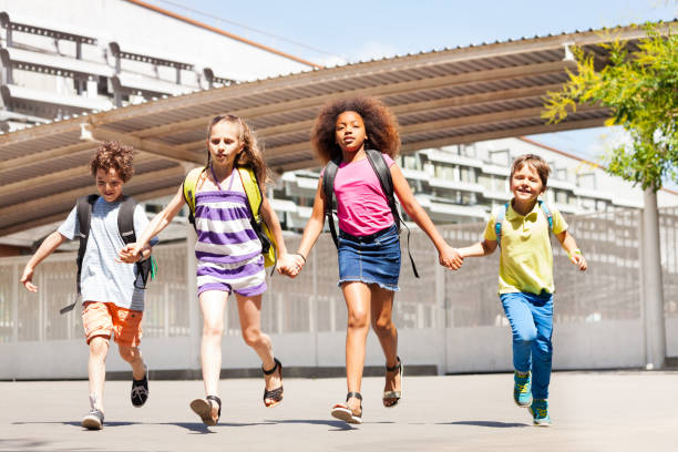 istock Excited kids run, hold hands near school building 831382390