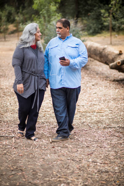 senior pareja mexicana con smartphone con auriculares - senior couple audio fotografías e imágenes de stock