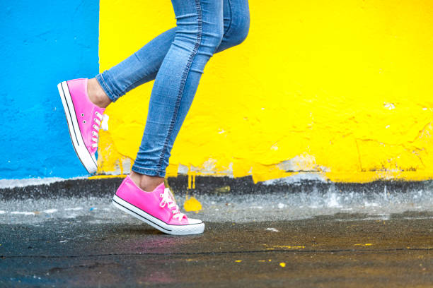 Woman in pink sneakers Woman in pink sneakers against yellow and blue wall jeans photos stock pictures, royalty-free photos & images