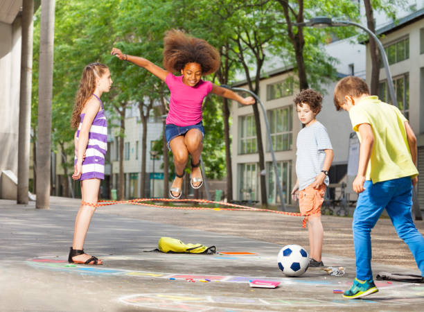 Group of kids play hopscotch on the school Group of kids elastic ropes together on the street jump rope stock pictures, royalty-free photos & images