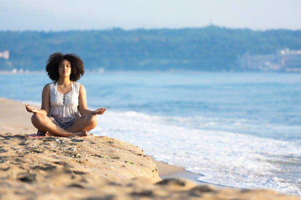 istock Africam woman sitting on sand and meditating 831383116