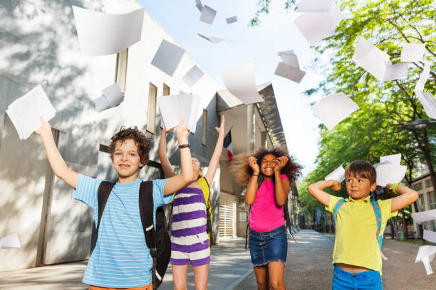 istock Kids throw textbook sheets in the air 831383662