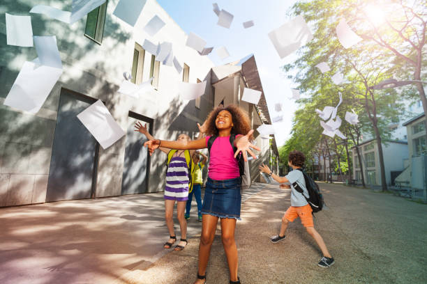 istock Girl throws papers happy and standing near school 831383876