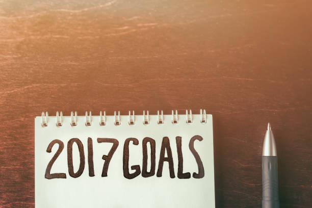 istock 2017 goals on paper note book background and pen on wood table, business 831383930
