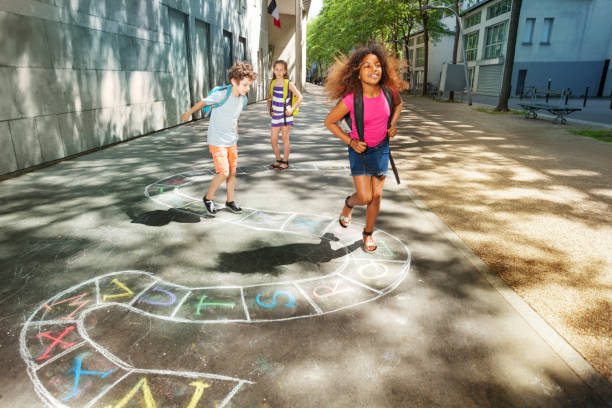 три счастливых детей школьного возраста играть hopscotch - hopscotch стоковые фото и изображения