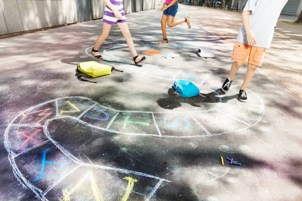 Closeup of little girl drawing with colorful chalks on the playground. Child playing with her mom the summer's games outside. Kid and mother drawing with chalk on the pavement. Activities for children