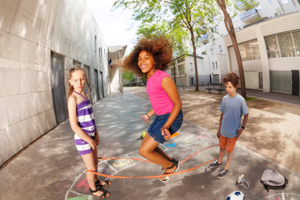 istock Girls and boy play elastic rope game together 831386820