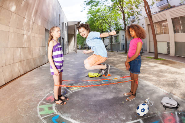 Kids jump over elastic rope smiling and happy with handsome boy in the air
