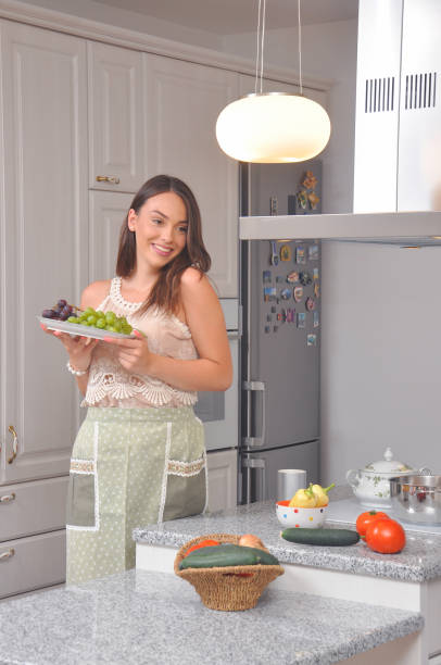 istock Beautiful smiling girl eats grapes in the kitchen. 831397262