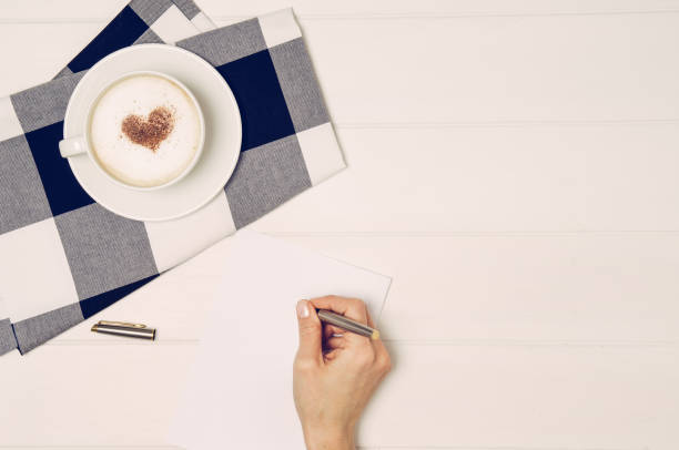 istock Female hand writing love letter on white table, top view 831403830