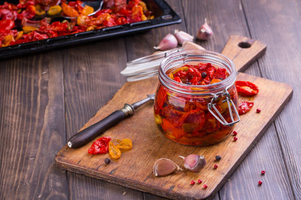 Sun dried tomatoes with olive oil in a jar. Old wooden desk and cutting desk.