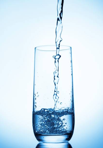 istock water pouring into glass on blue background 831432784
