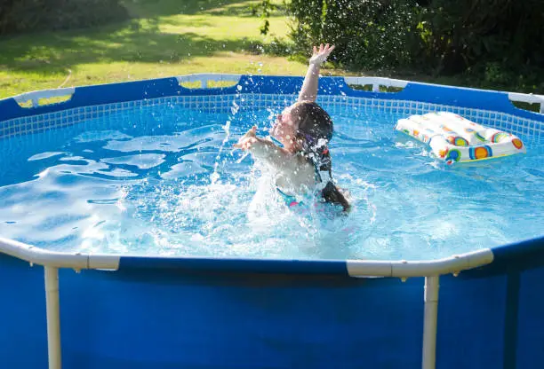 Eight years girl having fun in rubber swimming pool.