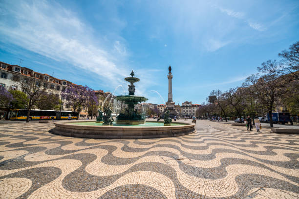 Lisbon, Portugal - May 3, 2017: Rossio Square in Lisbon city center with tourists sightseeing and eating in sidewalk cafes.