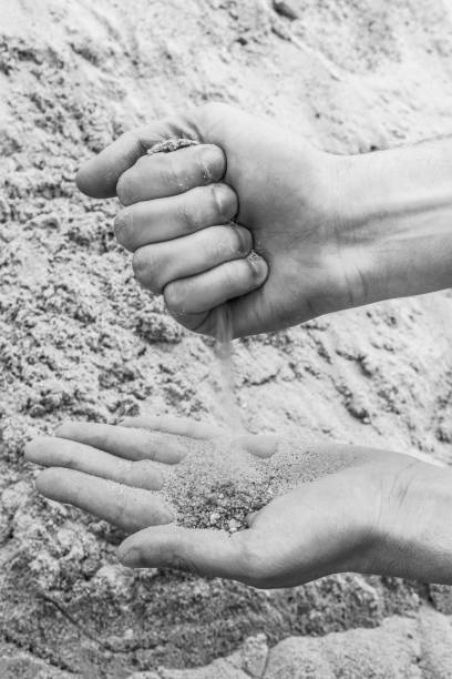 istock Hands of a young man pour sand from one hand to another 831452654