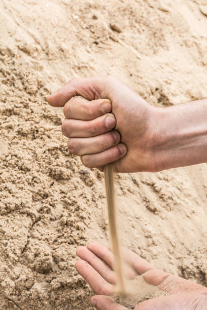 istock Hands of a young man pour sand from one hand to another 831452674