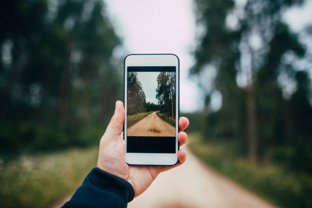 Taking a photo A human hand taking a picture of a footpath in a forest nature and landscapes camera stock pictures, royalty-free photos & images